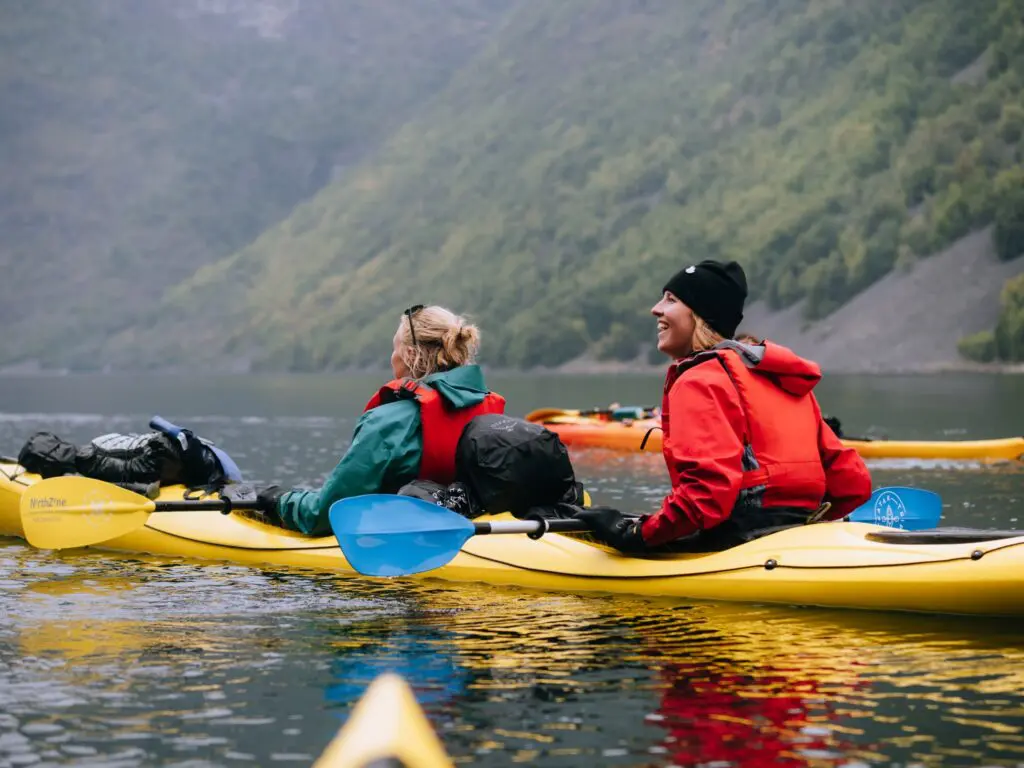 two women kayaking on a lake with mountains