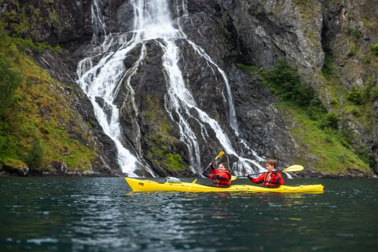zwei Personen, die an einem großen Wasserfall vorbeipaddeln