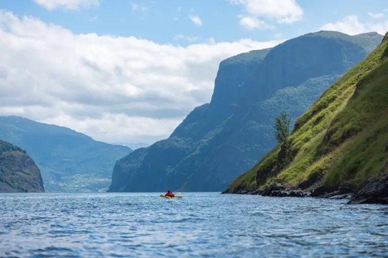 Kajakfahrer beim Paddeln in einem norwegischen Fjord mit steilen Bergen