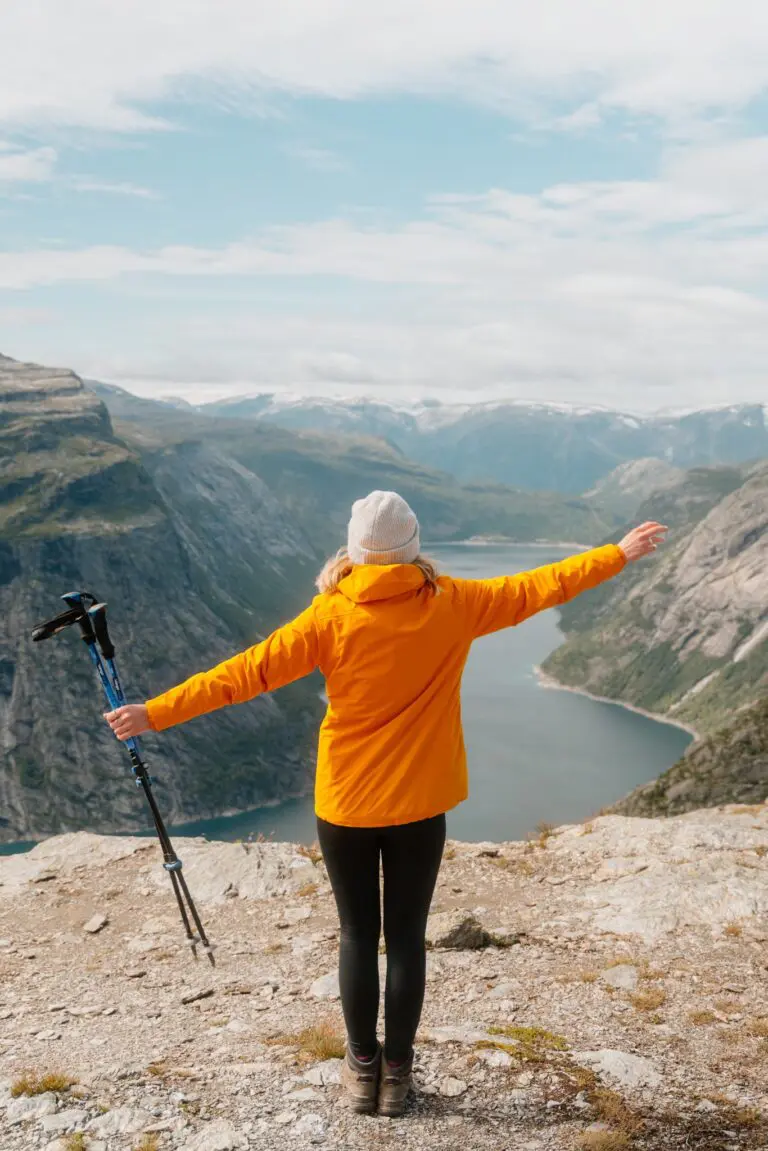 Wanderer mit ausgestreckten Armen mit Blick auf einen norwegischen Fjord