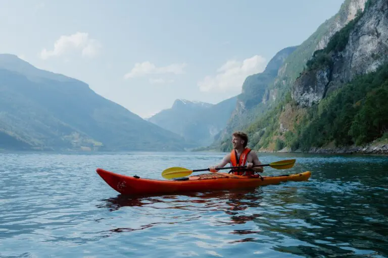 mann beim Kajakfahren in einem Fjord mit Bergen