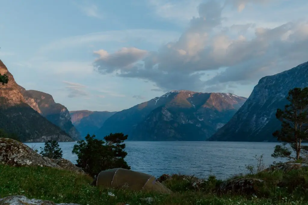 tent pitched by a fjord in Norway at sunset