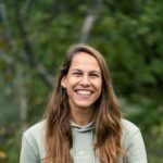 lächelnde Frau im Travelbase-Hoodie draußen