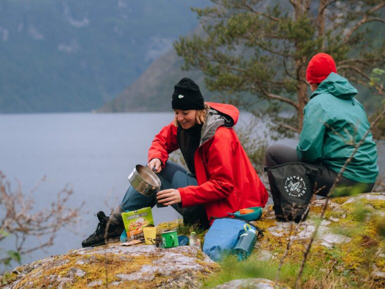 Frau kocht Wasser für Kaffee und ein Essenspaket - Kajakfahren - Norwegenfjord - Wandern in Norwegen - Kayaking - ab Flughafen Brüssel